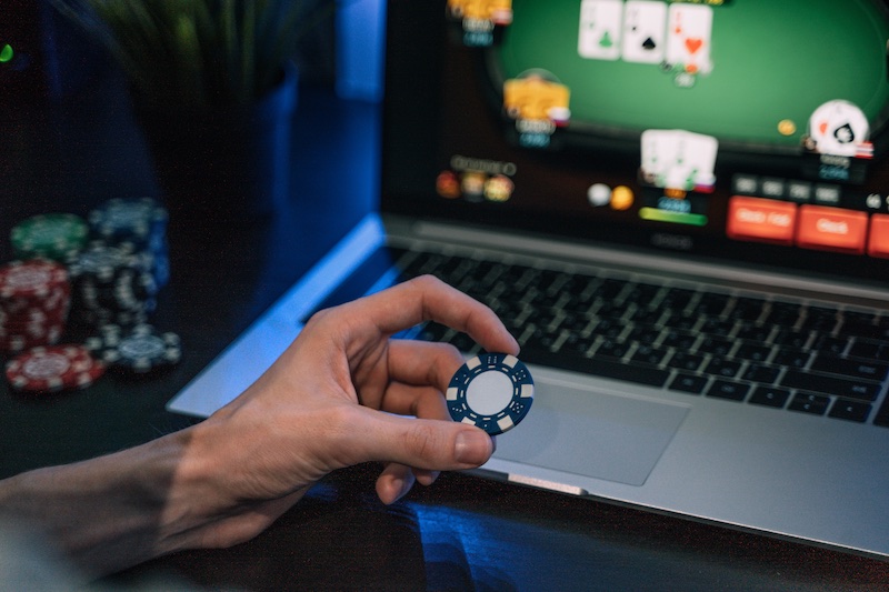 Ung man spelar onlinepoker på bärbar dator